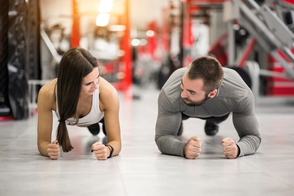 Moški in ženska izvajata vajo Plank, zasnovano za vse mišične skupine